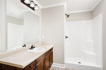 A bathroom with a sink, mirror, and bathtub at The Meadows Apartments in Florence, AL